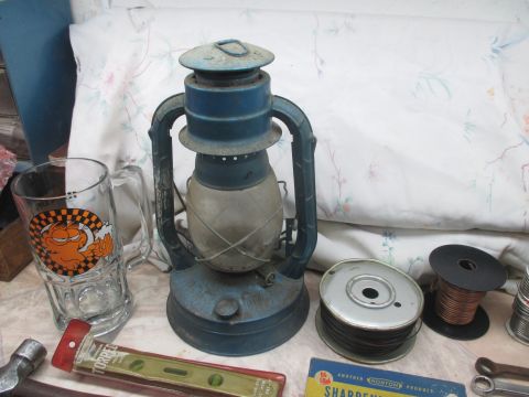 2004 Aston Martin Virage - A vintage blue lantern sits on a table with various other items, including a Garfield mug and a level.