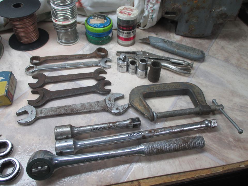 Assortment of wrenches, sockets, a C-clamp, and other tools on a patterned surface