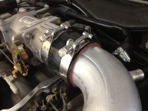 1998 Ford Crown Victoria - This image shows a close-up view of an engine's throttle body and an aluminum intake pipe assembly.