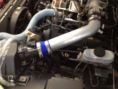 1998 Ford Crown Victoria - Aftermarket intake pipes installed in an engine bay, silver tubing and blue silicone couplers.