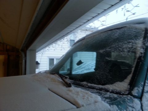 1996 Ford Bronco - A vehicle sits covered in snow, partially inside a garage with Christmas lights visible.