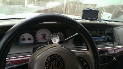 2000 Mercury Grand Marquis - The interior of a 2000 Mercury Grand Marquis shows the dashboard, steering wheel, and a mounted GPS unit.