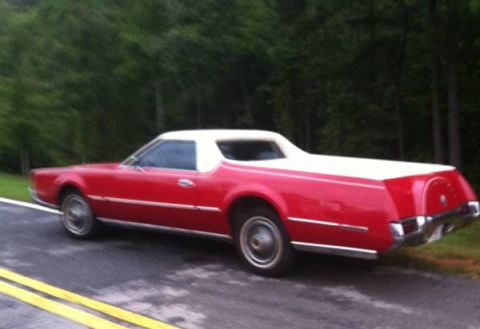 1973 Ford Ranchero - This red and white coupe utility features a distinctive spare tire cover on its tailgate, suggesting a model from the early to mid-1970s.