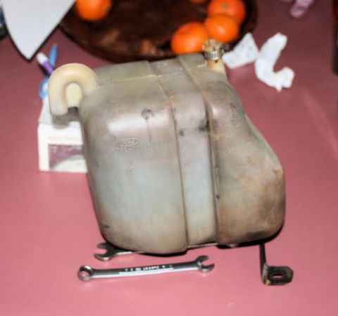 1976 Ford Ranchero - A plastic coolant reservoir with a Ford logo is shown, supported by two wrenches.
