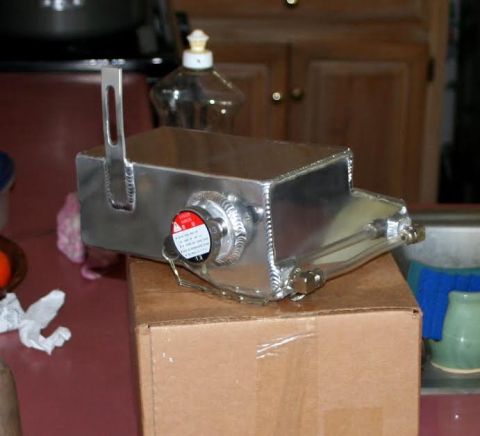 1976 Ford Ranchero - A shiny aluminum radiator overflow tank sits on a cardboard box, ready for installation.