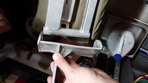 1985 Toyota 4Runner - Metal bracket assembly with visible welds, held by a hand. A plastic jug is nearby.