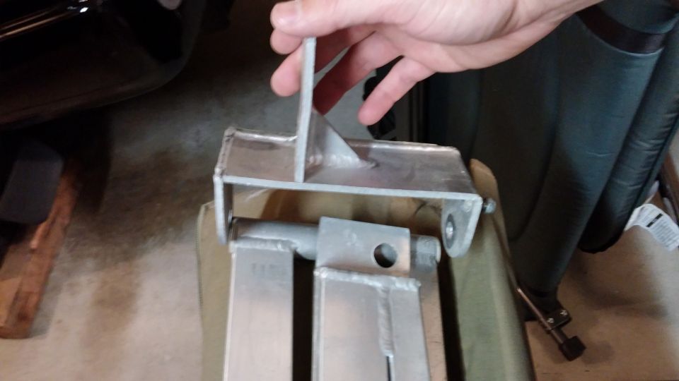 hand holding metal bracket with bolts and holes