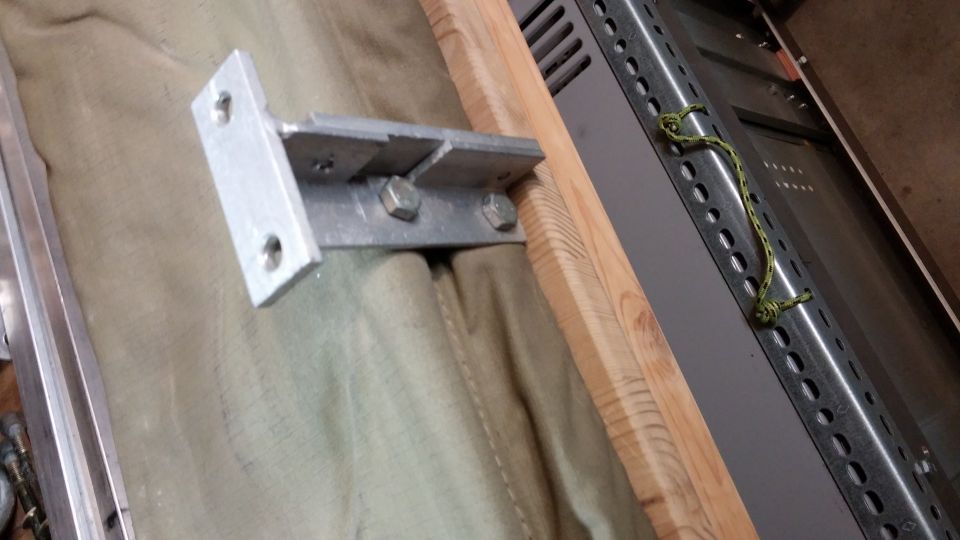 Metal bracket bolted to wooden frame over tan fabric