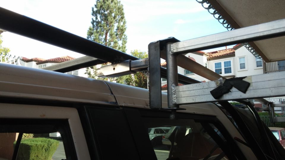 Silver roof rack with black bars attached to the side of a white SUV
