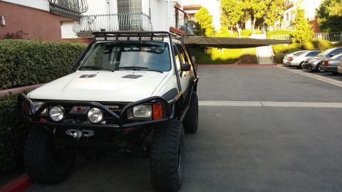 1985 Toyota 4Runner - This white Toyota 4Runner, likely from the late 1980s, is equipped with an aftermarket bumper and a deployed awning.