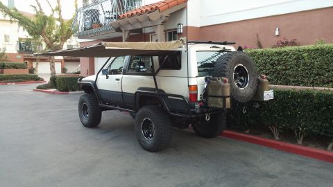 1985 Toyota 4Runner - Modified 1985 Toyota 4Runner parked outdoors, equipped with an extended awning and auxiliary fuel cans.