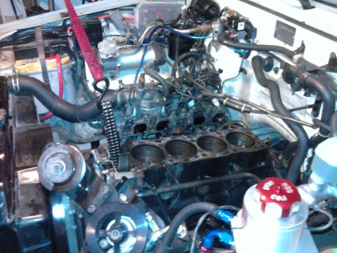 1985 Toyota 4Runner - Engine block undergoing repair, with pistons removed and a red lifting strap attached to the engine assembly.
