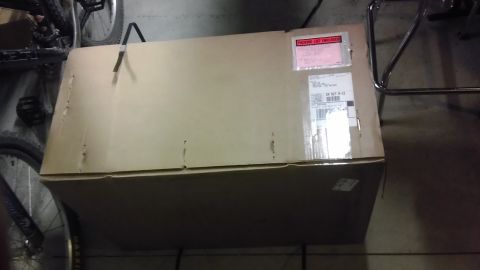 1985 Toyota 4Runner - A large cardboard box sits in a garage, with shipping labels visible on its surface.