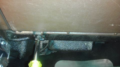 1985 Toyota 4Runner - A screwdriver is used to work on a bracket under the dashboard.
