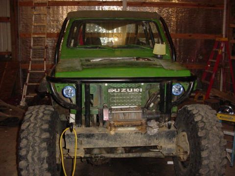1992 Ford Bronco - Front view of a green off-road vehicle with a winch and prominent SUZUKI branding on the grille.