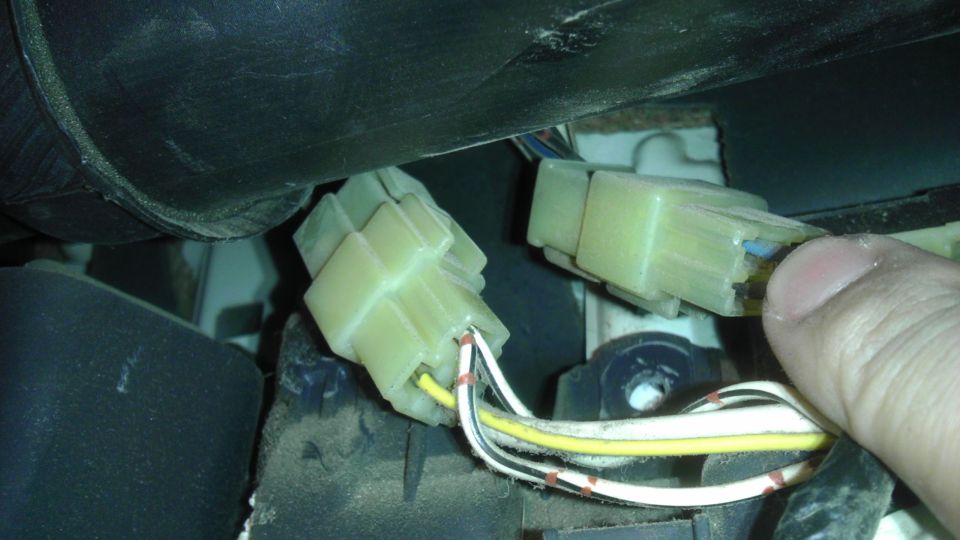 Close-up of two yellow electrical connectors with wires, one being held by a thumb