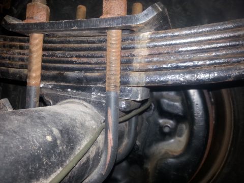 1996 Ford Bronco - Close-up view of a vehicle's leaf spring and axle assembly, showing rusted U-bolts.