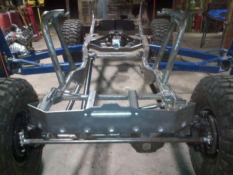 1985 Jeep CJ7 - Custom Jeep CJ frame and suspension assembly in a garage setting.