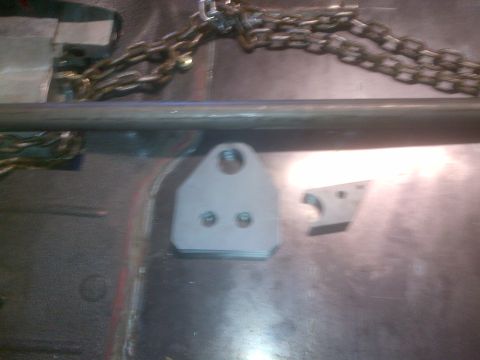 1985 Jeep CJ7 - Metal brackets and chains are laid out on a workshop floor.
