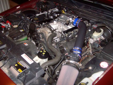 2004 Ford Crown Victoria - Engine bay view showing an aftermarket cold air intake system installed on a vehicle. A warning label is visible on a component in the fore…
