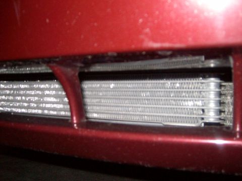 2004 Ford Crown Victoria - An aftermarket engine oil cooler is visible behind the red bumper of a vehicle.