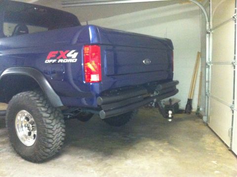 1982 Ford Bronco - Rear view of a blue Ford Bronco parked in a garage, showing the FX4 Off Road decal and aftermarket bumper.