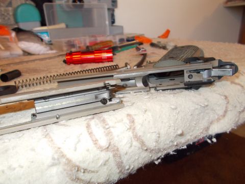 2012 Ford Mustang - A firearm is disassembled, with its components and tools laid out on a textured surface, suggesting maintenance or repair.