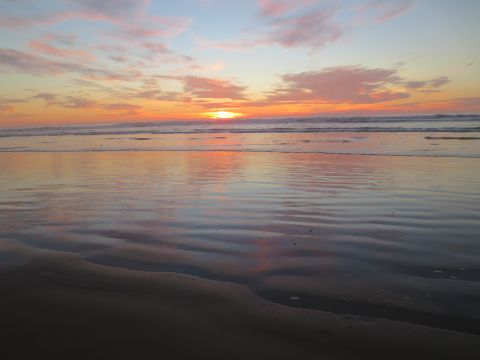 1989 Ford Bronco - Sunset over the ocean with colorful clouds reflected on wet sand at the beach.