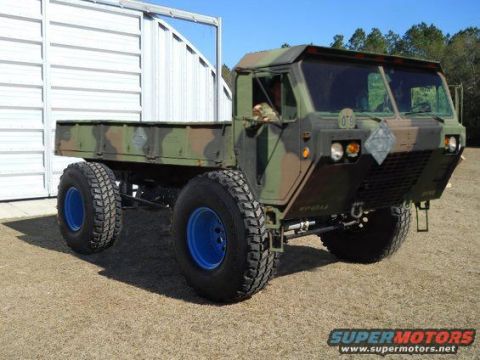1994 Ford Bronco - This military truck features a flatbed and a camouflage paint scheme, with bright blue rims on its large tires.