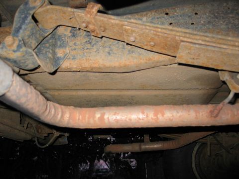 1995 Ford Bronco - The underside of a vehicle shows significant rust on the exhaust system and frame components.
