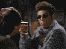 2000 Mercury Grand Marquis - A man in sunglasses and a distinctive sweater holds up a glass of beer, appearing to be in a bar or social setting.