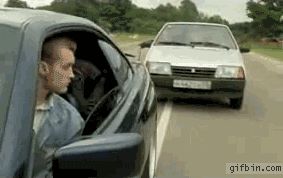 2000 Mercury Grand Marquis - A man in a dark car observes a white car as they drive down a road together.