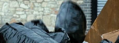 2000 Mercury Grand Marquis - Black trash bags are piled up in front of a brick wall and a dumpster.