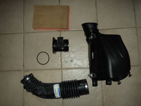 2004 Mercury Grand Marquis - Air intake components including a filter, MAF sensor, and flexible intake tube are laid out on a tiled floor.