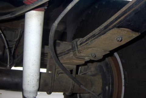 1994 Ford Bronco - Close-up view of the rear leaf spring and shock absorber assembly on a vehicle.