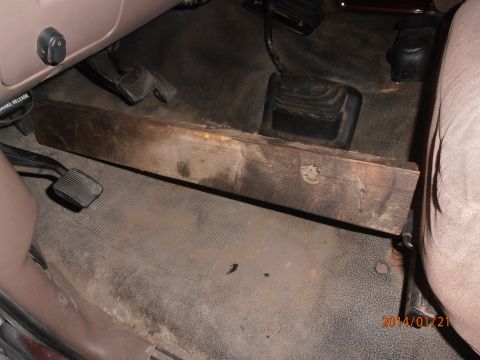1996 Ford Bronco - The interior of a vehicle shows floor pedals and a wooden block placed on the floor.