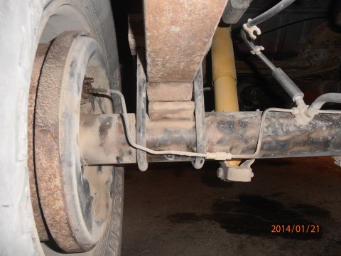 1996 Ford Bronco - Close-up view of the rear suspension and drum brake assembly, showing leaf springs and a yellow shock absorber.