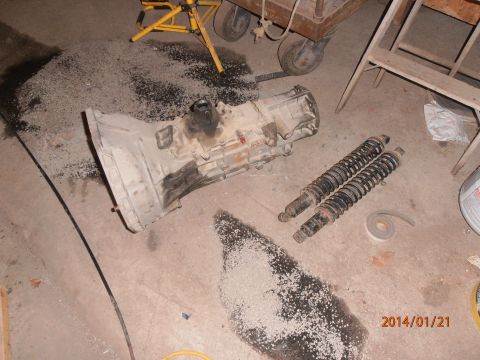 1996 Ford Bronco - Transmission and shock absorbers are laid out on a concrete floor, possibly for repair or replacement.