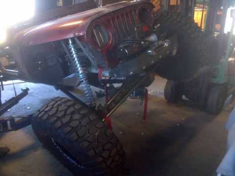 1985 Jeep CJ7 - This red Jeep CJ-series shows its front end, large off-road tires and exposed suspension components during a build.