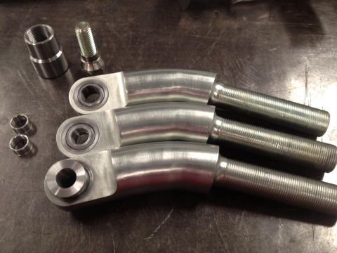 1985 Jeep CJ7 - Close-up of several metal suspension components laid out on a workbench surface.