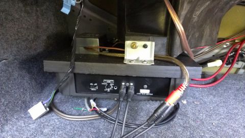 1996 Lincoln Town Car - Close-up of a car amplifier and wiring installed in the trunk, with visible RCA connectors and power cables.