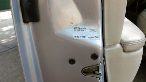 1996 Lincoln Town Car - A close-up view of a vehicle's door jamb reveals a calibration sticker and part of the interior seat.