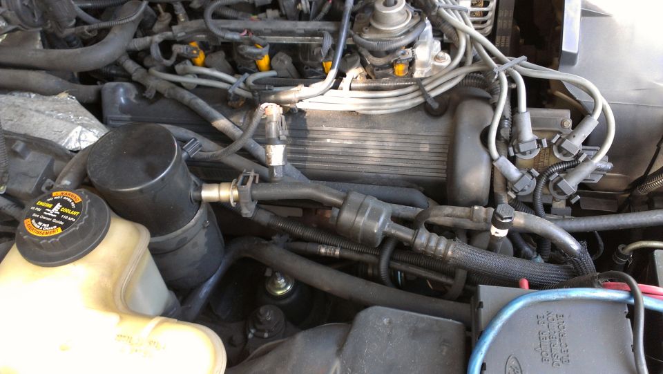 Engine bay with coolant reservoir, air intake, spark plug wires, and engine cover visible