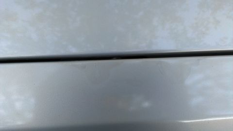 1996 Lincoln Town Car - Close-up of a silver car panel a black trim line and the Supermotors logo.