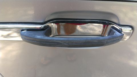 1996 Lincoln Town Car - Detail shot of a car's exterior door handle, showing chrome trim and a rubber grip.
