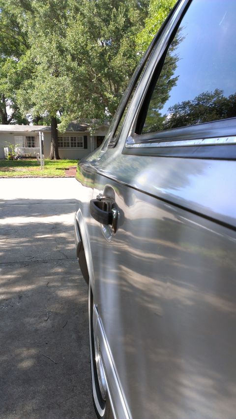 1996 Lincoln Town Car - A close-up shot of a silver sedan's side profile, showing the door handle and reflections on the body.