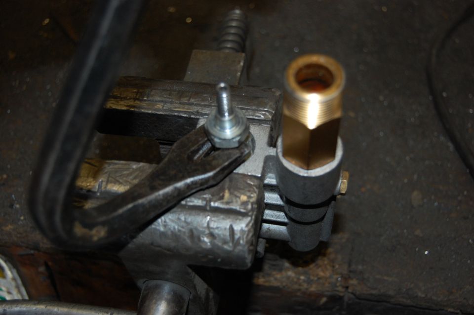 Metal part held in vise with brass fitting