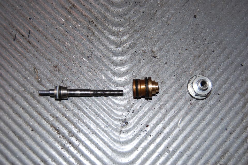 Valve stem, brass valve body, and nut on textured surface