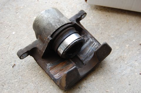 1994 Ford Bronco - Brake caliper part shown on concrete surface.