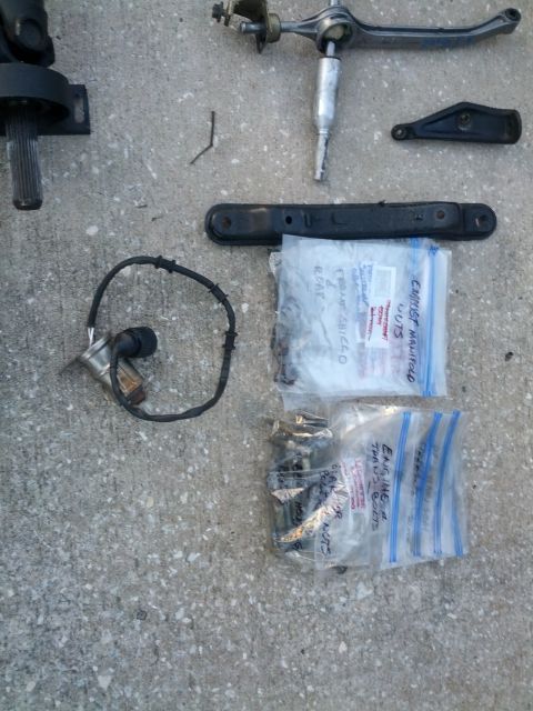 1989 BMW 3 Series - Assorted automotive parts and hardware laid out on a concrete surface.